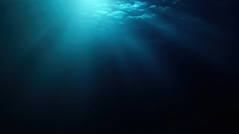 Faint rays of light filtering from the surface into near-black deep blue water