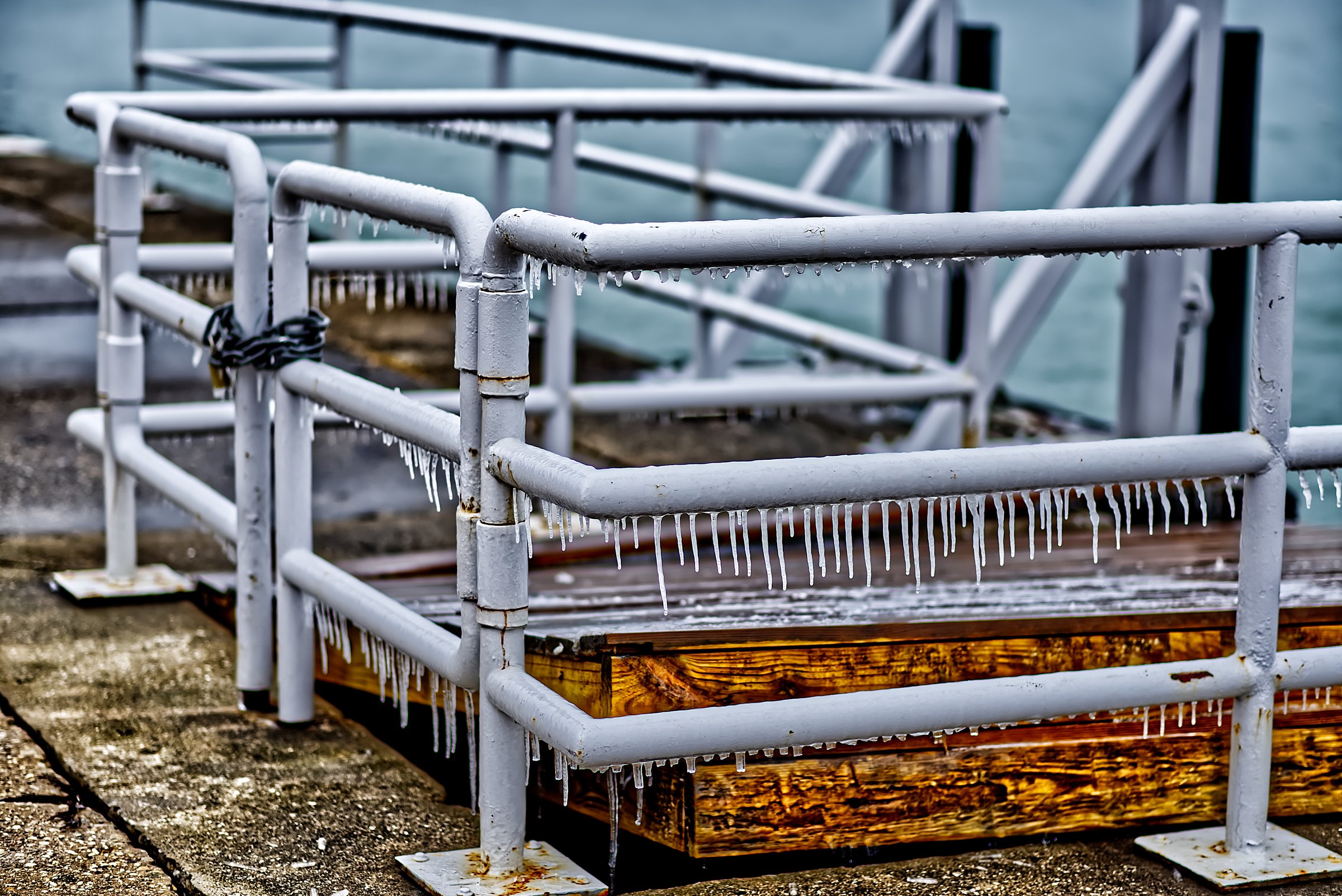 Icicles hanging from grey steel railings above weathered timber decking