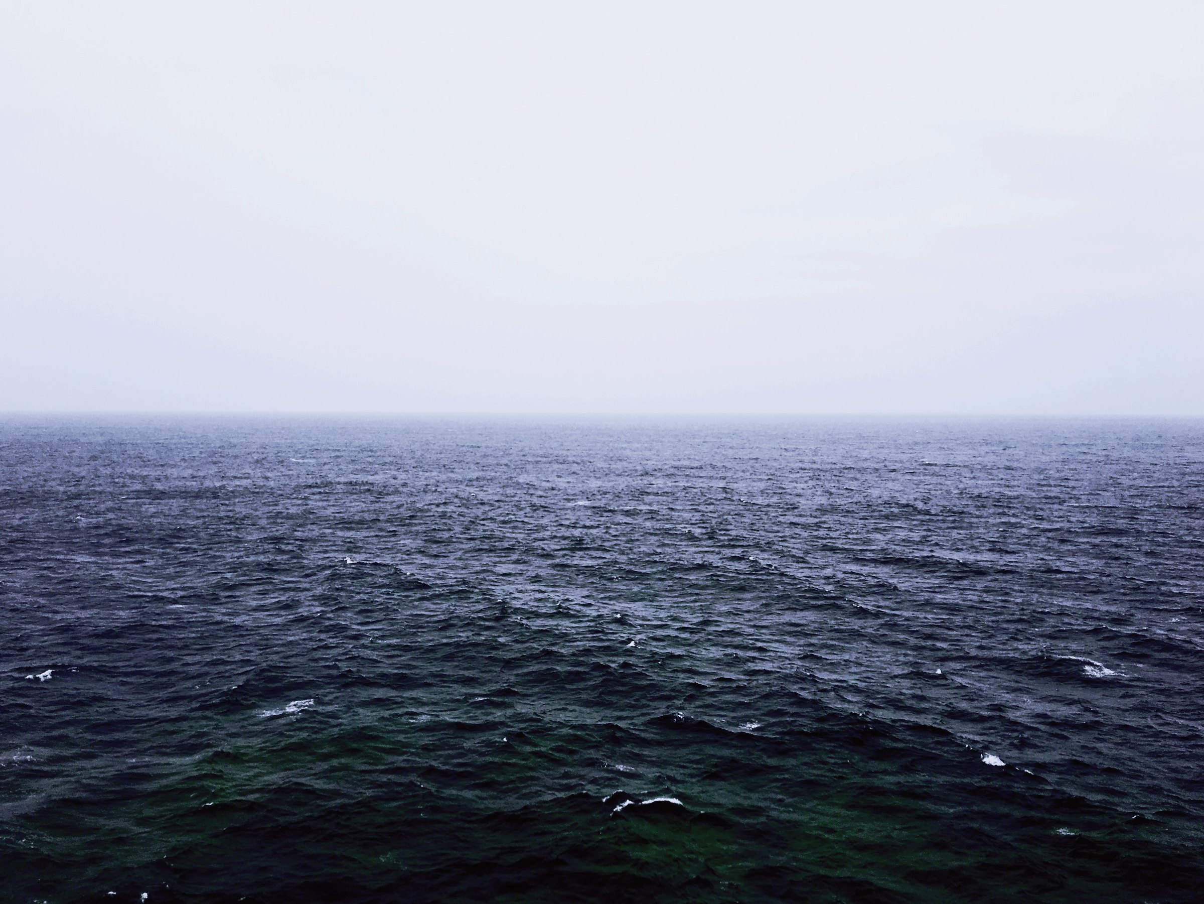 Dark open sea meeting a pale fog bank on the horizon