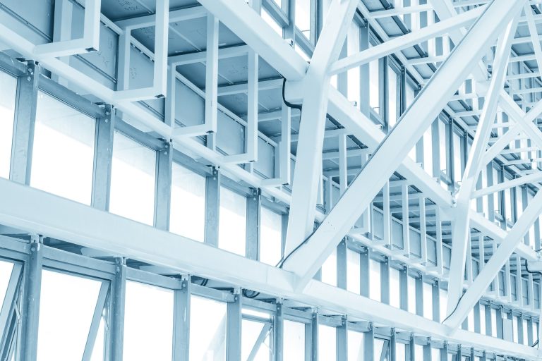 Pale white steel roof trusses and glazing seen from below in soft light