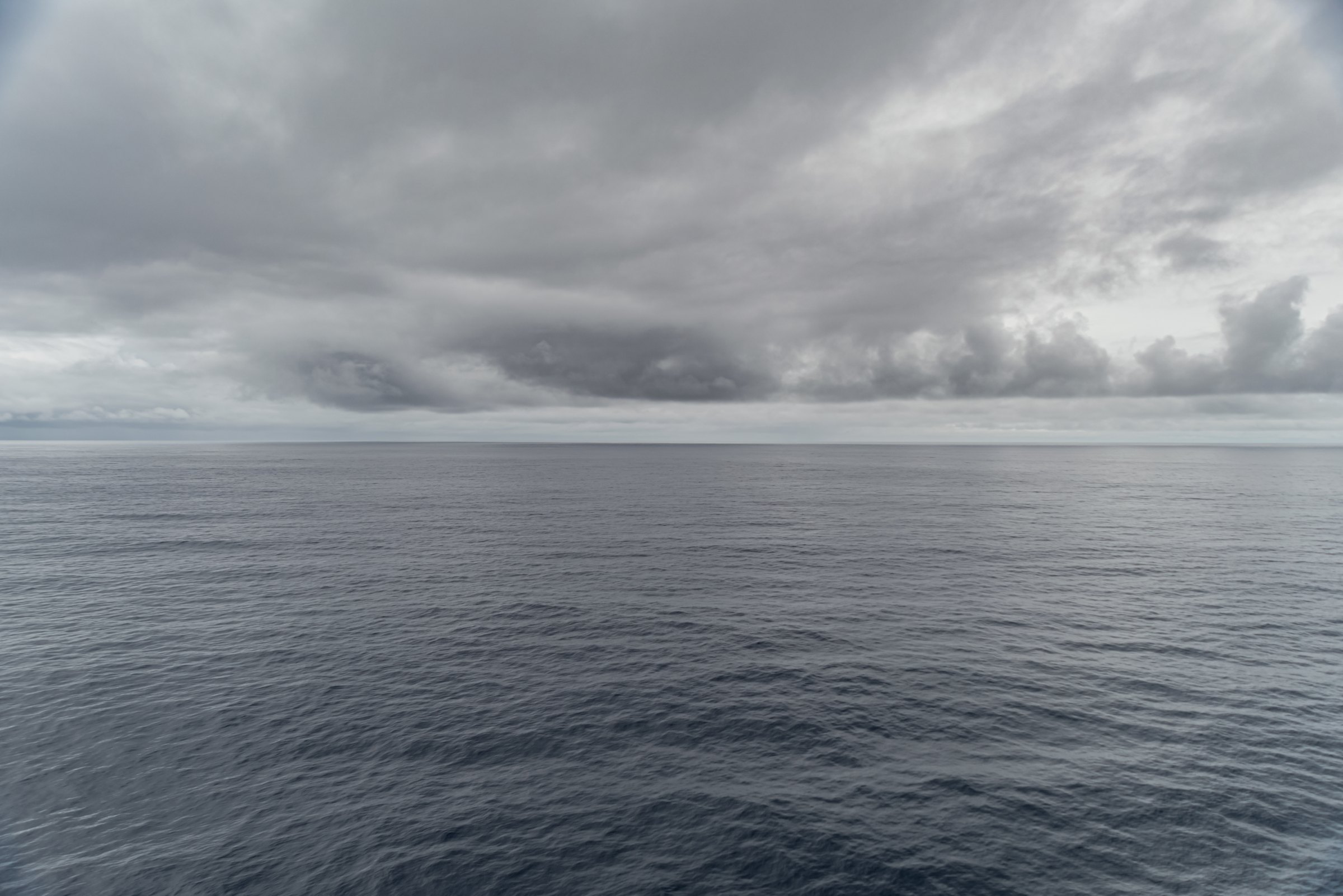 Calm grey open sea stretching to the horizon under a heavy, layered overcast sky