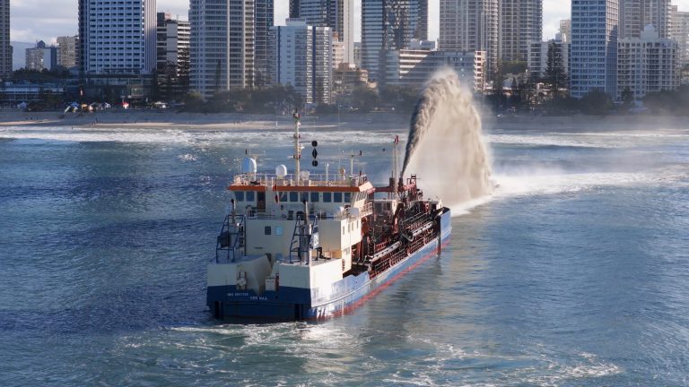 Dredging vessel discharging a plume of sediment and water near the coast