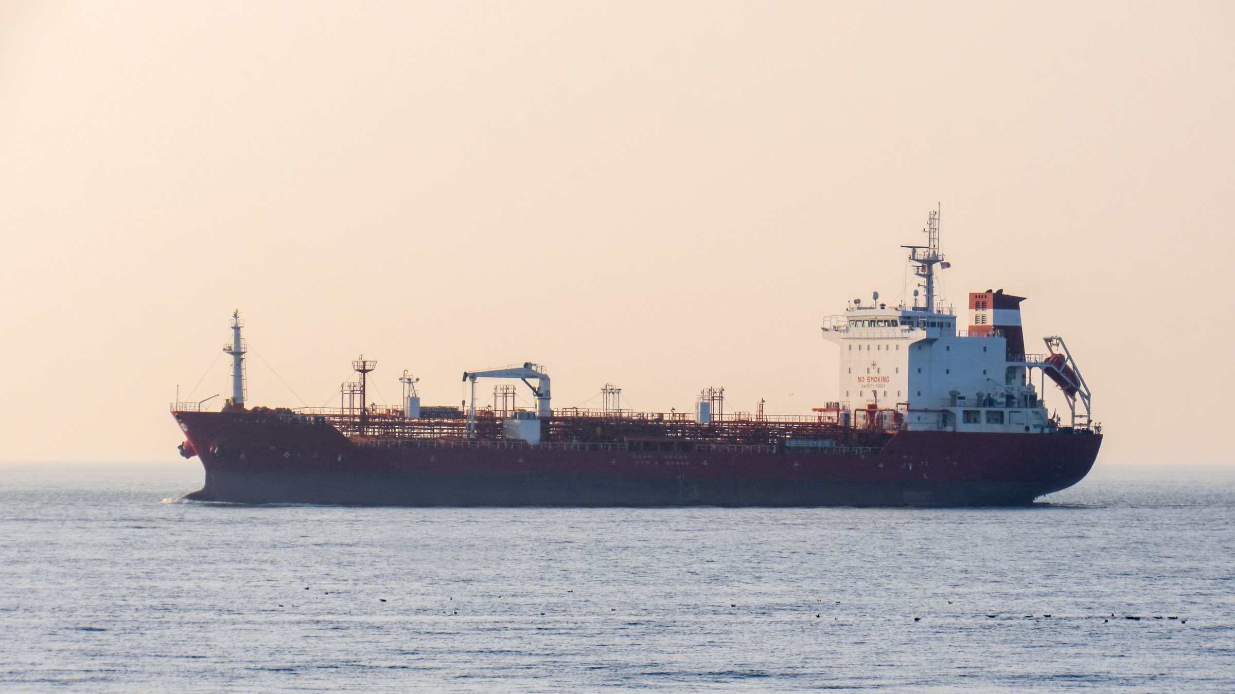 Product tanker at anchor on a calm sea in soft evening haze