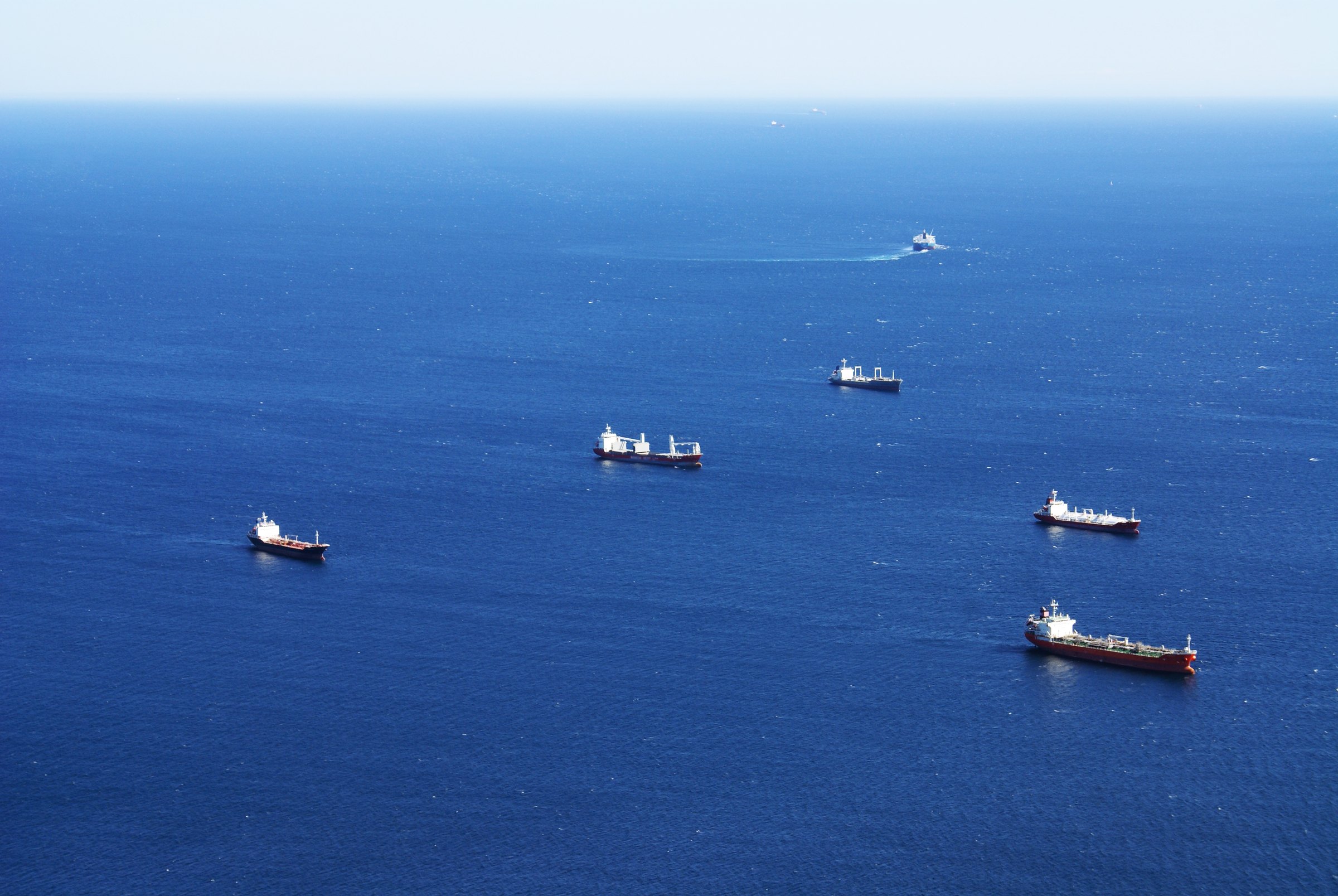 Several ships spread across deep blue open sea, seen from high above